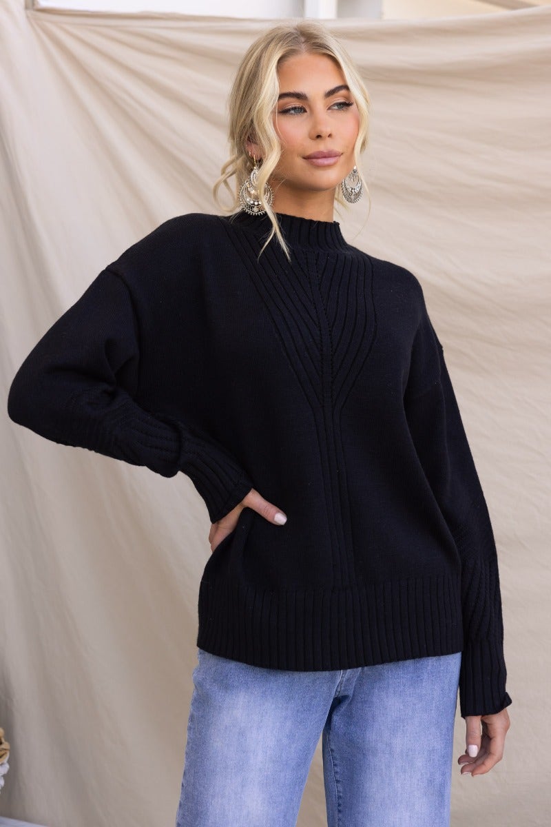 Black ribbed knit Cuba jumper with mock neckline, worn with relaxed fit jeans, perfect for stylish casual wear.