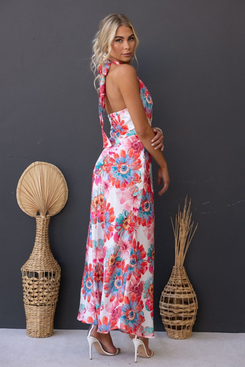 Model wearing floral print satin maxi dress with high tie neckline, showing back view against a neutral background.