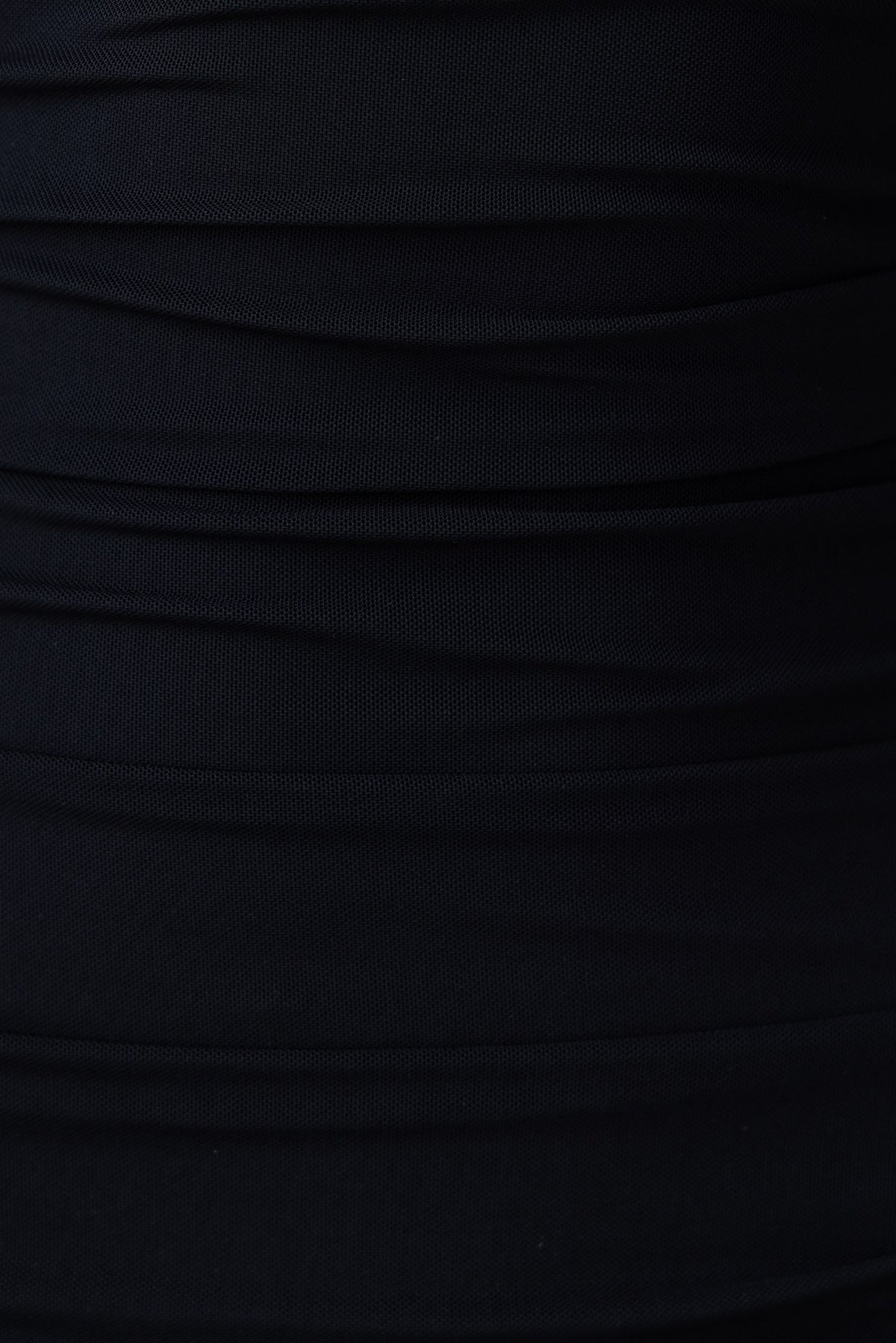Close-up of black fabric with gathered texture, showcasing the luxurious feel of a bodycon dress.