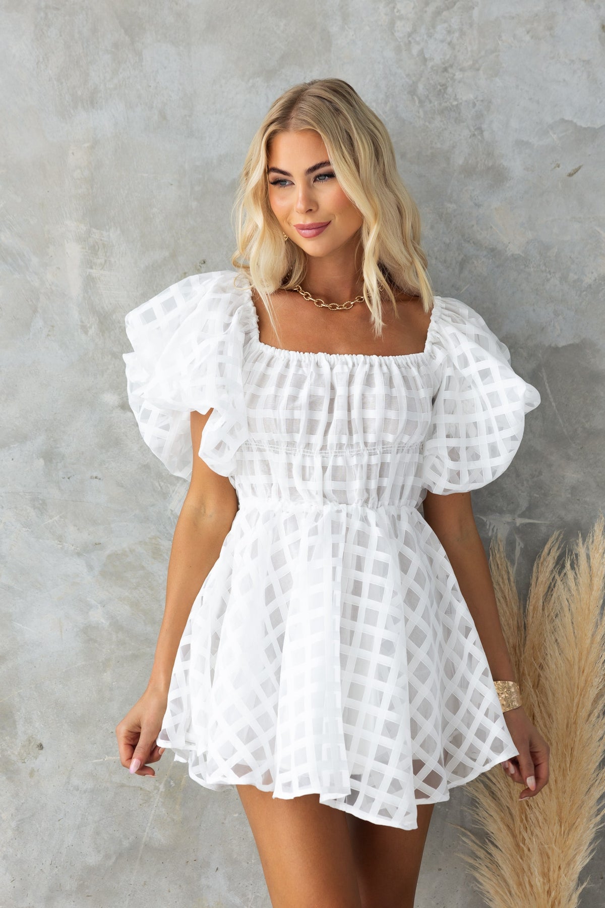 Model wearing a white Zerali dress with off-shoulder elastic neckline and puff sleeves, showcasing a stylish summer look.