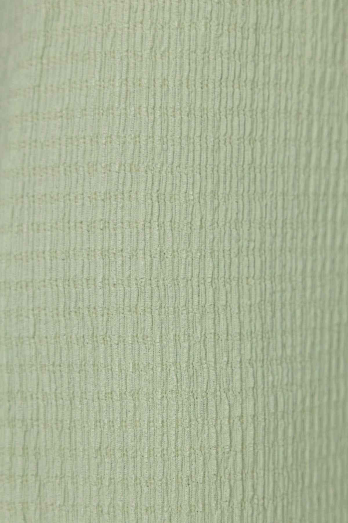 Close-up texture of light green polyester fabric, showcasing a lightly textured pattern for the Sachie Top.