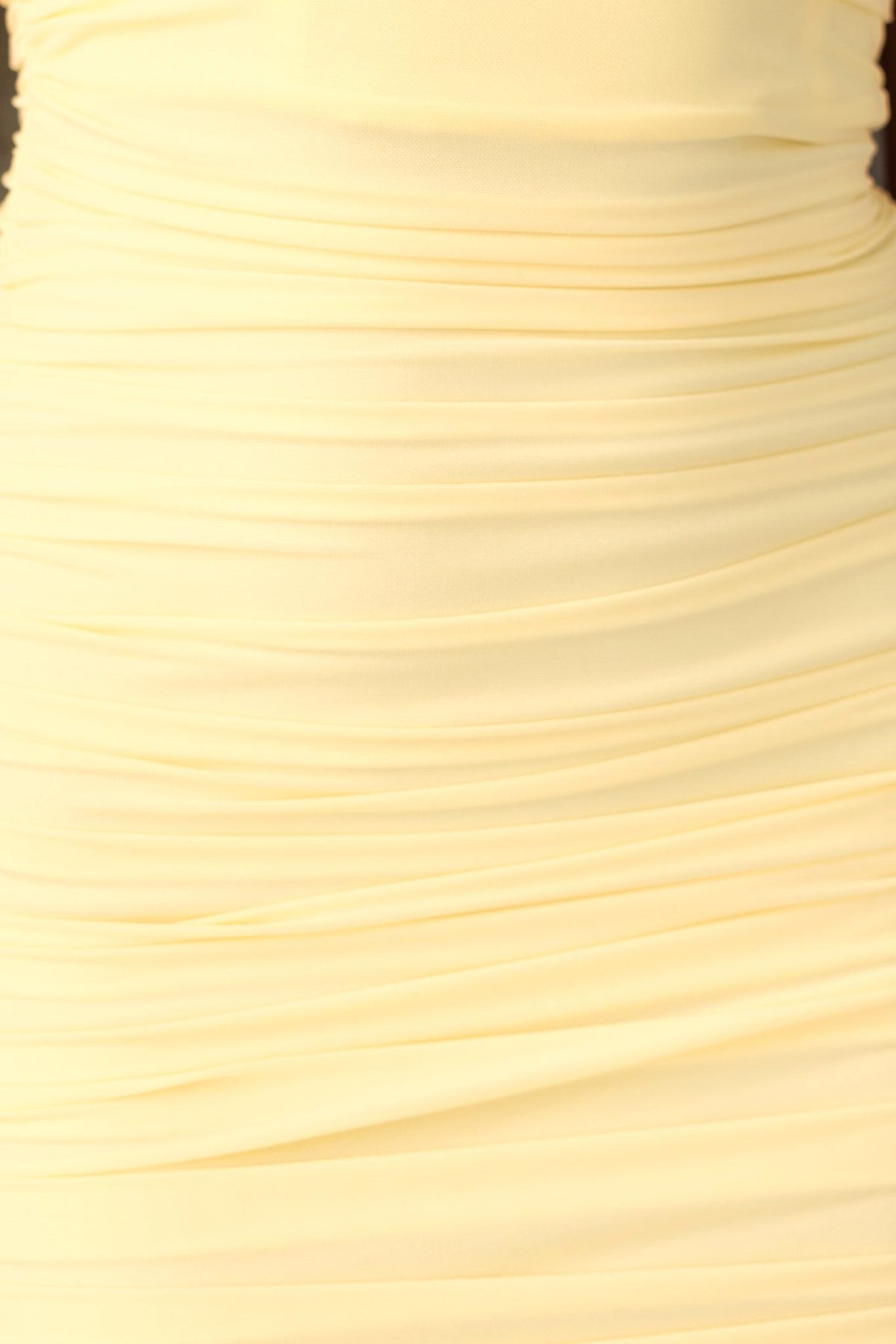 Close-up of the ruched yellow mesh overlay fabric of the Dayara Dress, showcasing its stretch and seamless design.
