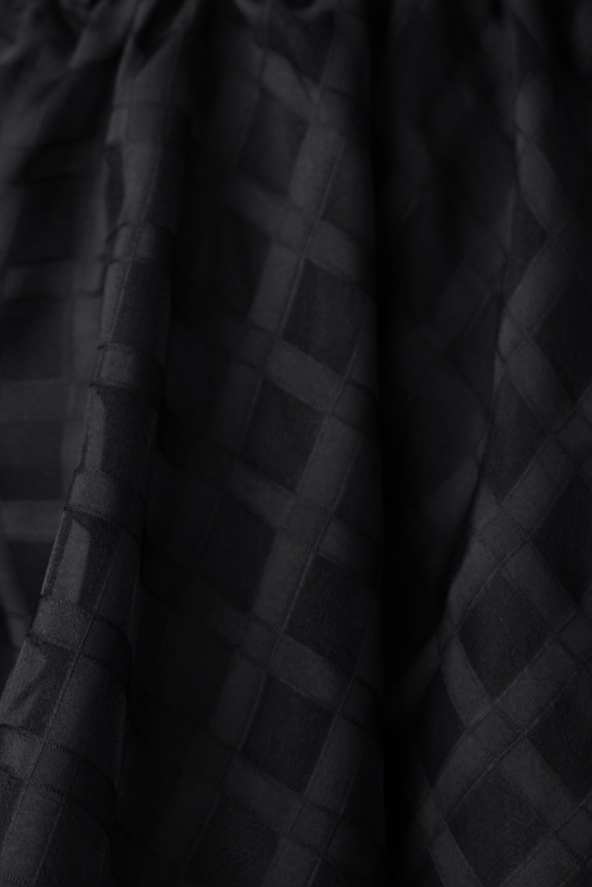 Close-up of the textured fabric of the Zerali black dress showcasing a grid pattern.