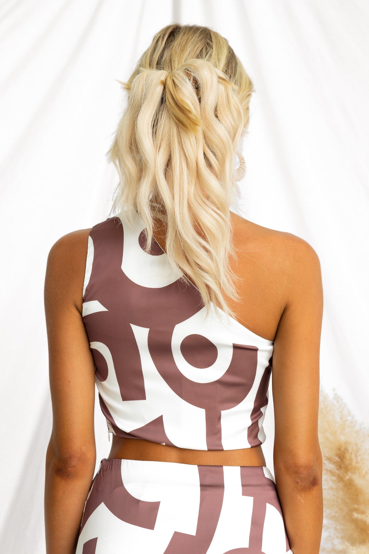 Vella Top in one-shoulder style featuring a satin look with abstract patterns, viewed from the back.