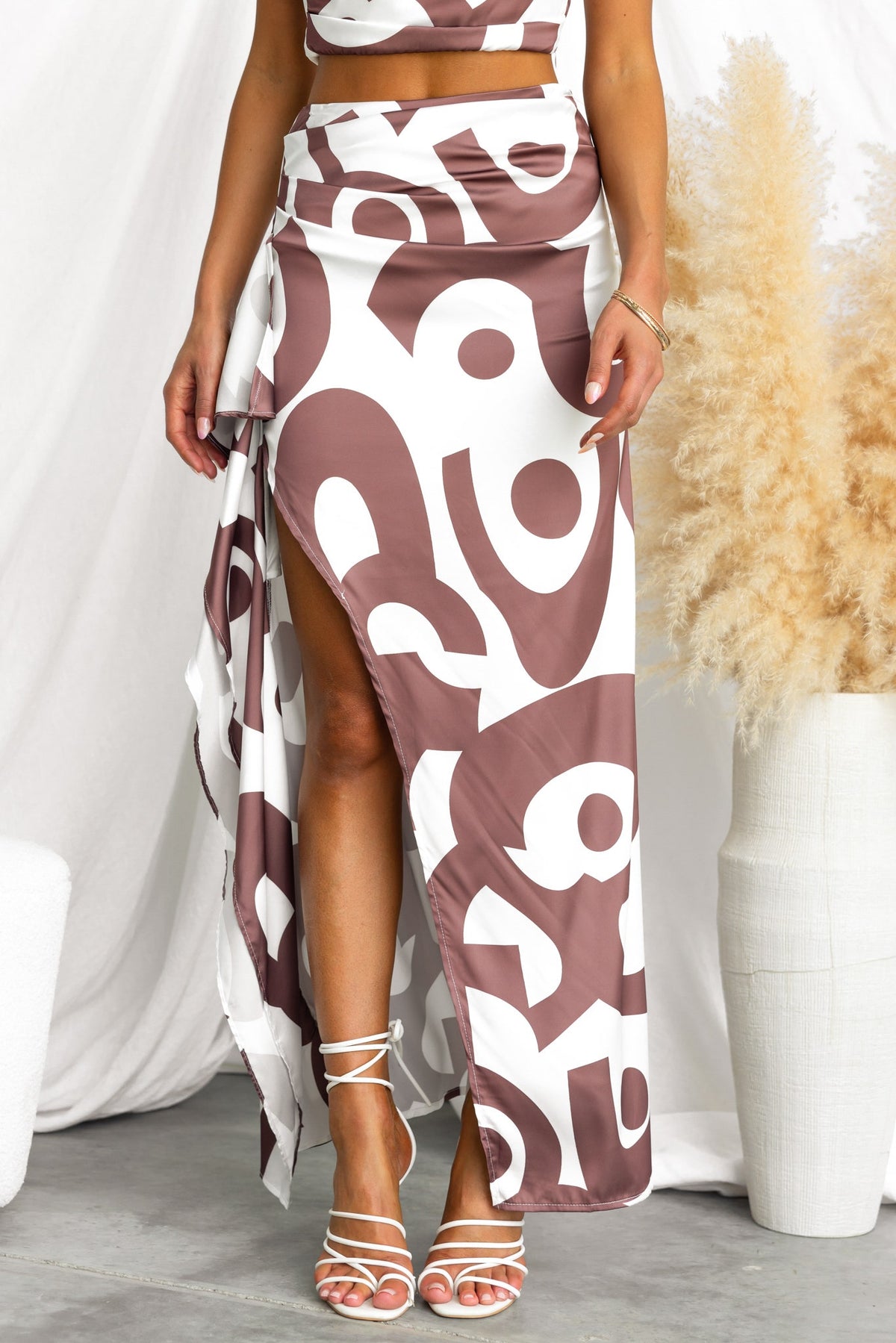 Vella Maxi Skirt with mid-high waist, side split, and ruffle trim, displayed in a stylish outfit.