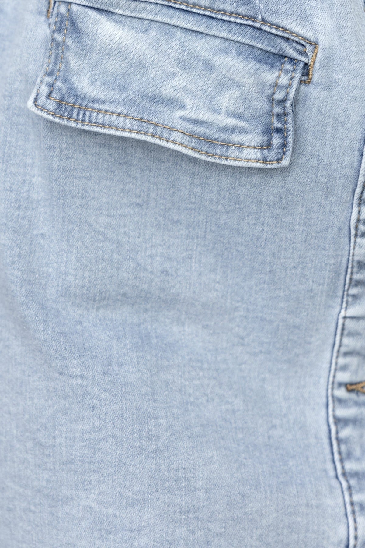Close-up of the back pocket on a light wash denim dress, showcasing soft fabric and detailed stitching.