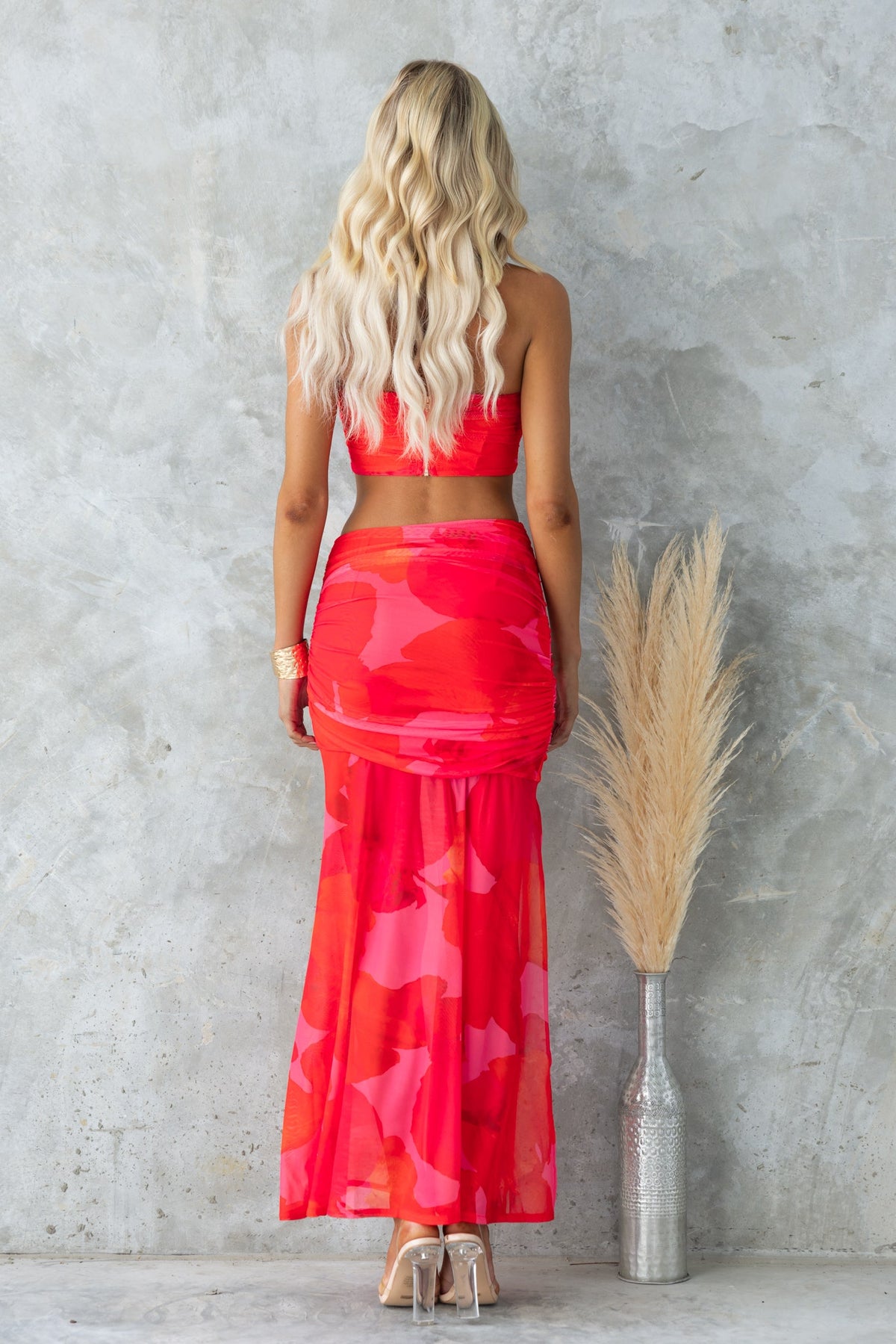 Back view of the Odessia Set featuring a strapless top and a mid-high waist mesh overlay skirt in vibrant red.