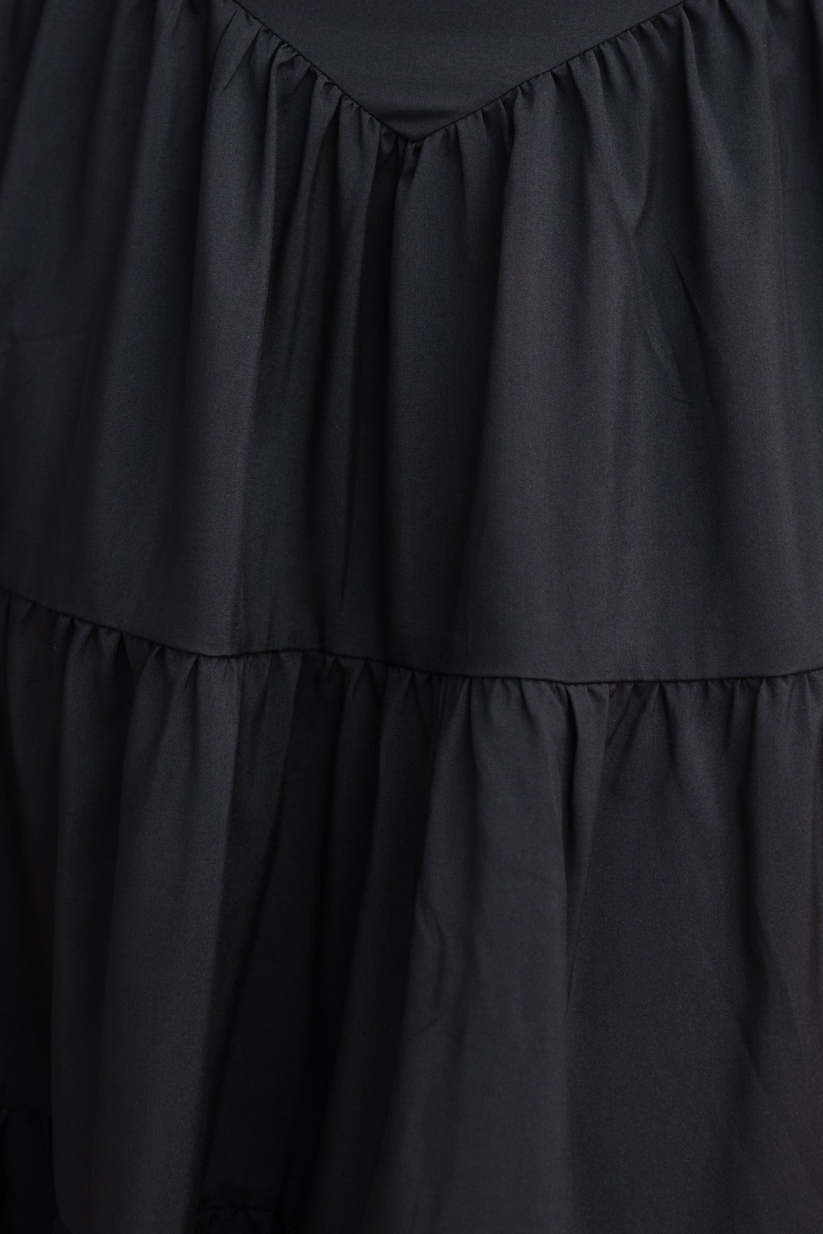Close-up of the black Merle Midi Dress featuring tiered ruffles and a soft cotton texture.