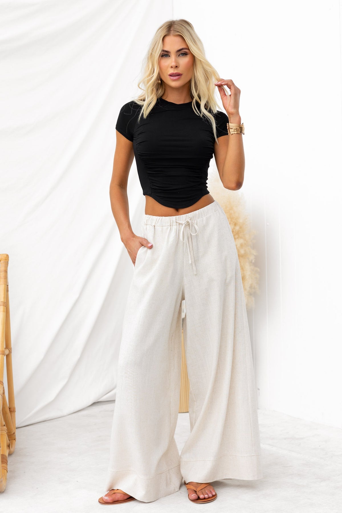 Model wearing a black Pippie Top paired with cream wide-leg pants, showcasing a stylish, casual outfit.