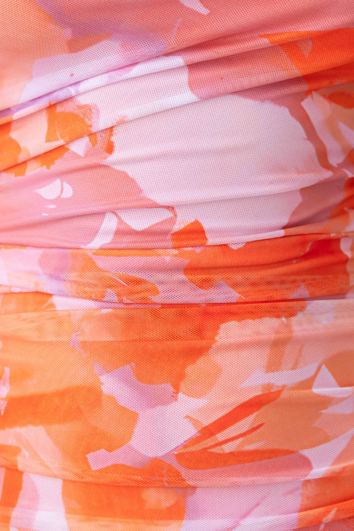 Close-up of Stolen Kiss Maxi Dress fabric featuring vibrant orange and pink hues with a ruched design.