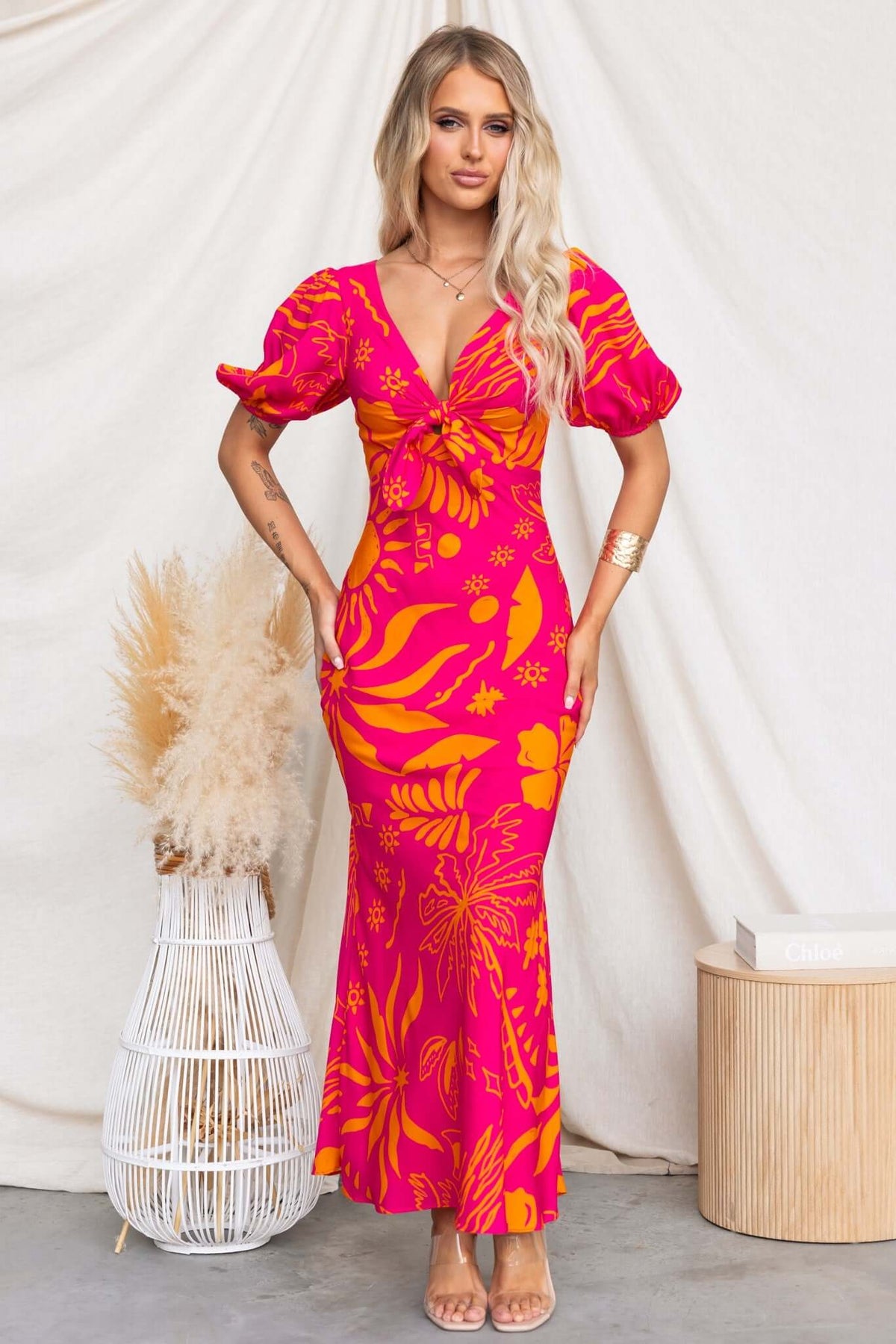 Nowah Maxi Dress in vibrant pink with floral pattern, featuring tie bust and puff sleeves, perfect for summer occasions.