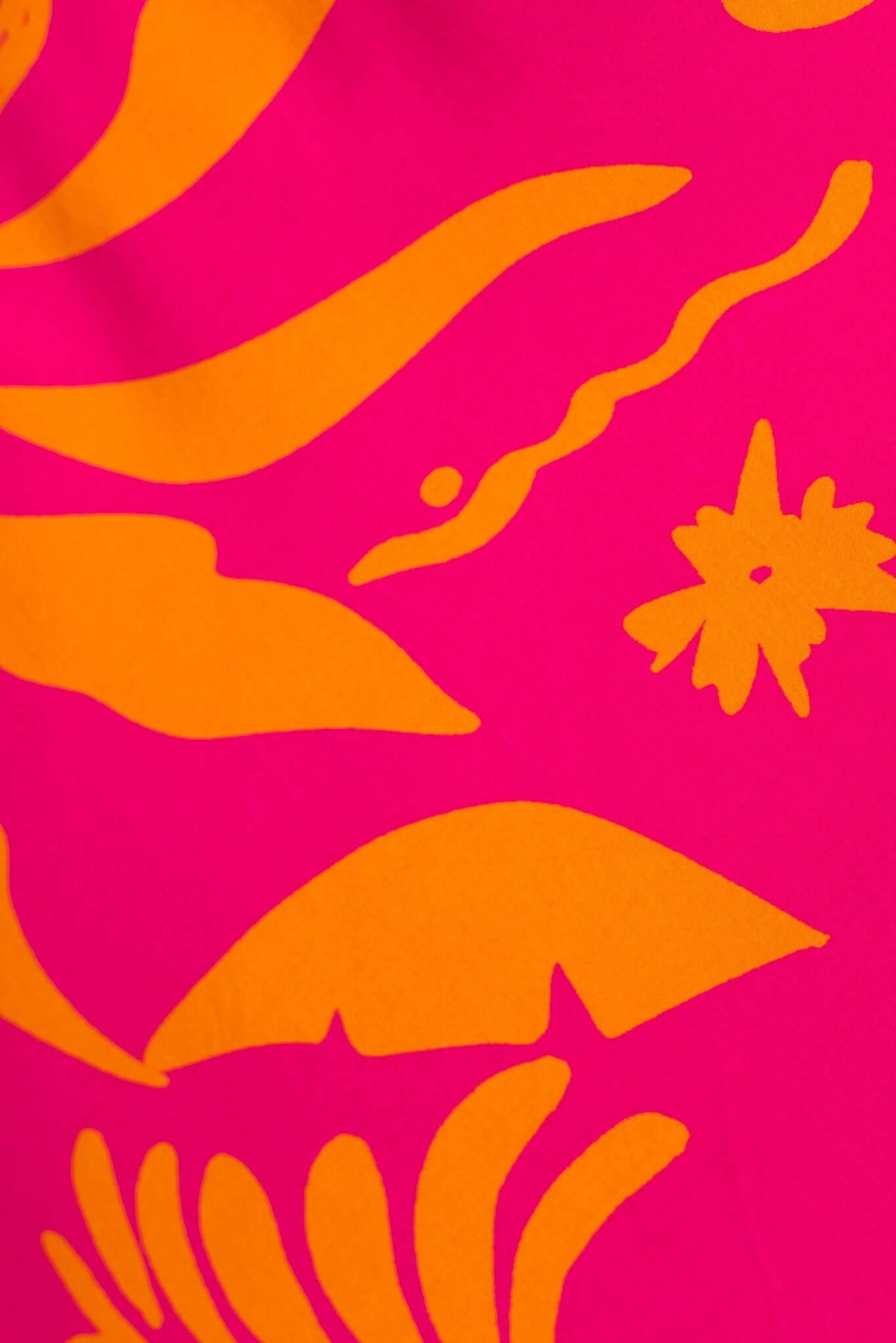 Close-up of vibrant pink fabric with bold orange floral patterns, showcasing a tropical design for the Nowah Maxi Dress.