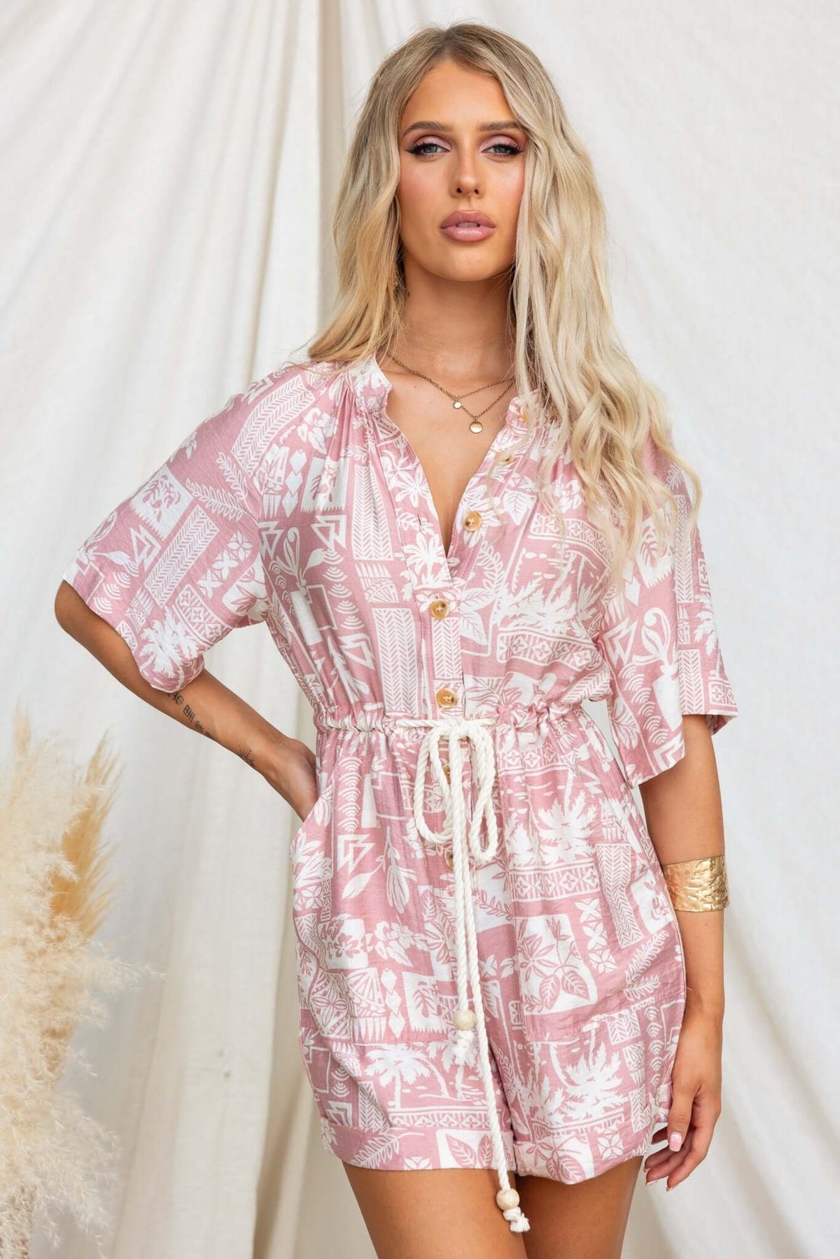 Huxley Playsuit in pink with button-up front, elastic waistband, and hip pockets, styled for a relaxed fit.