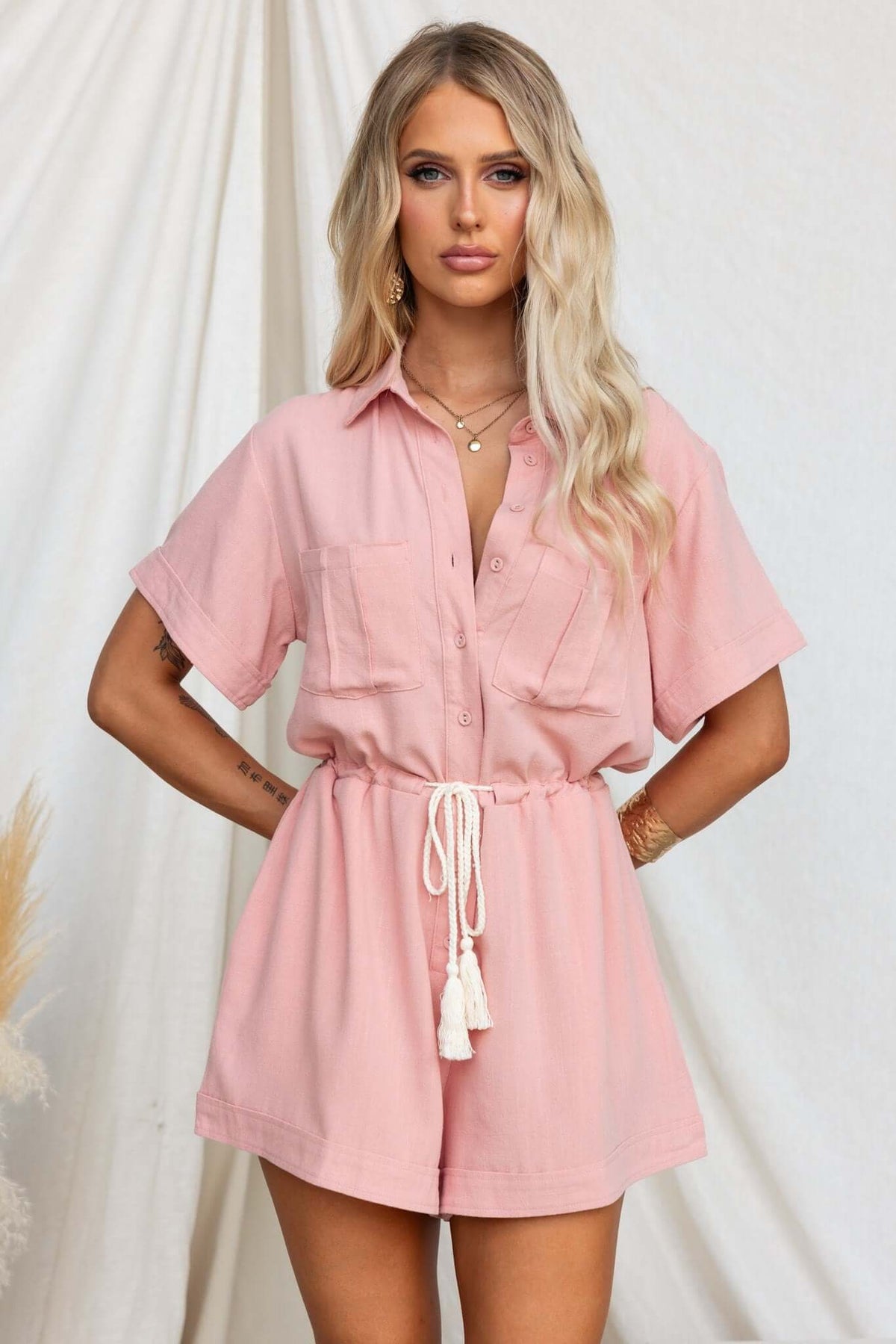 Barre playsuit in soft pink with collar, button-up front, drawstring waist, and pockets, styled on a model.