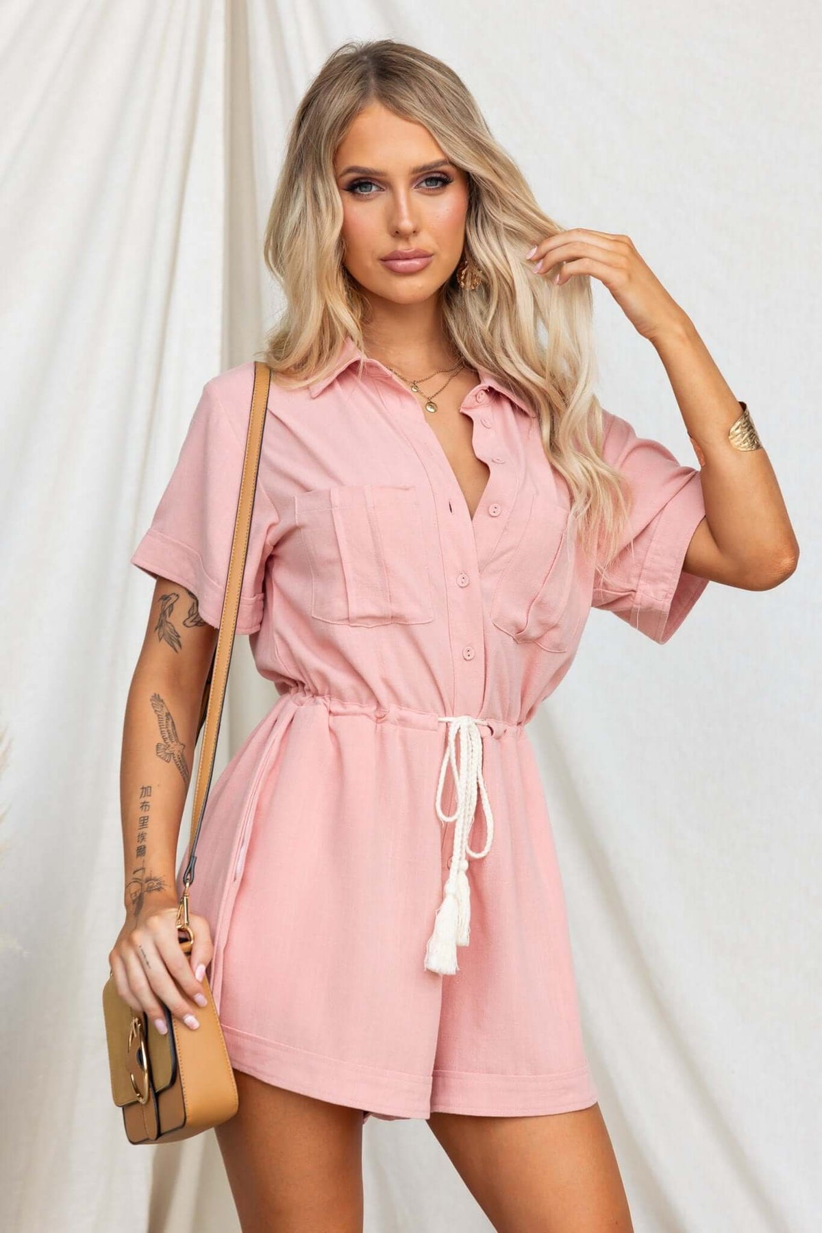Model wearing a pink Barre Playsuit with collar, button-up front, drawstring waist, and pockets.