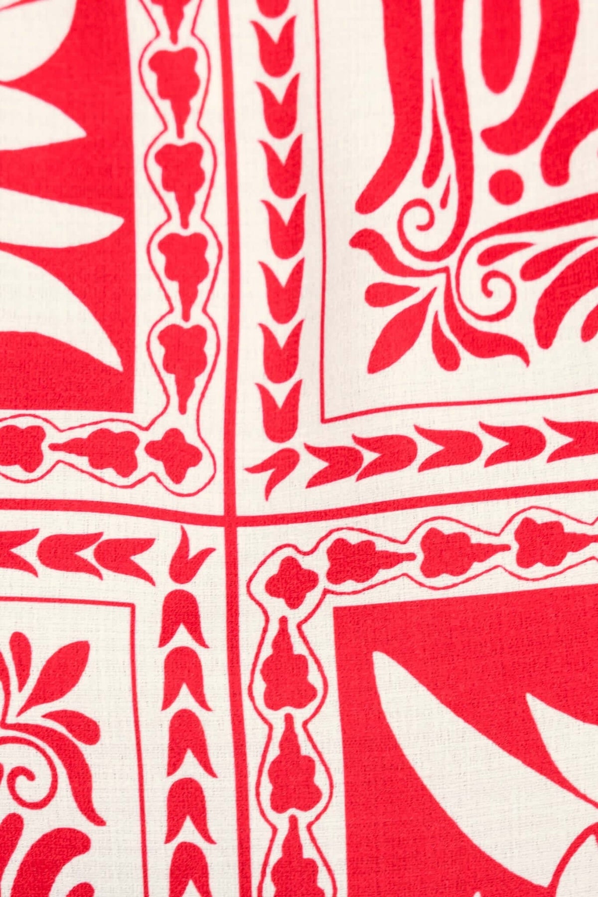 Close-up of red and white floral patterned fabric featuring intricate designs and borders.