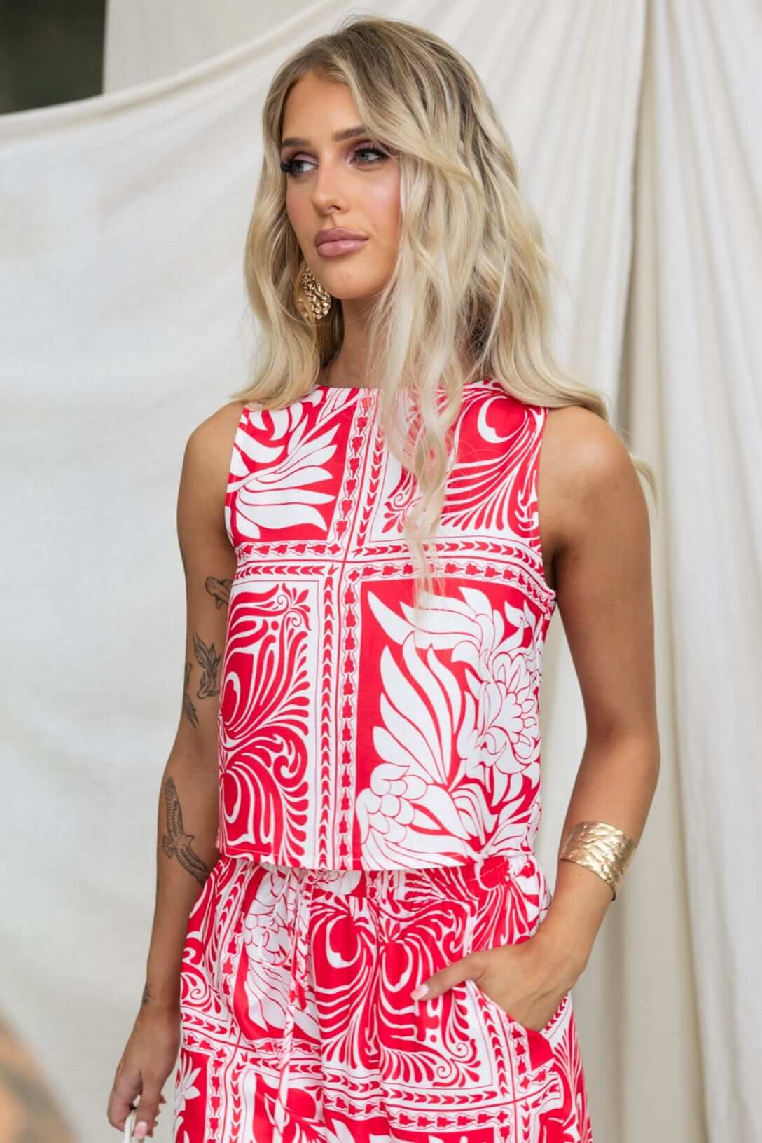 Model wearing the Powell Top, a vibrant red and white floral print blouse with a relaxed fit.