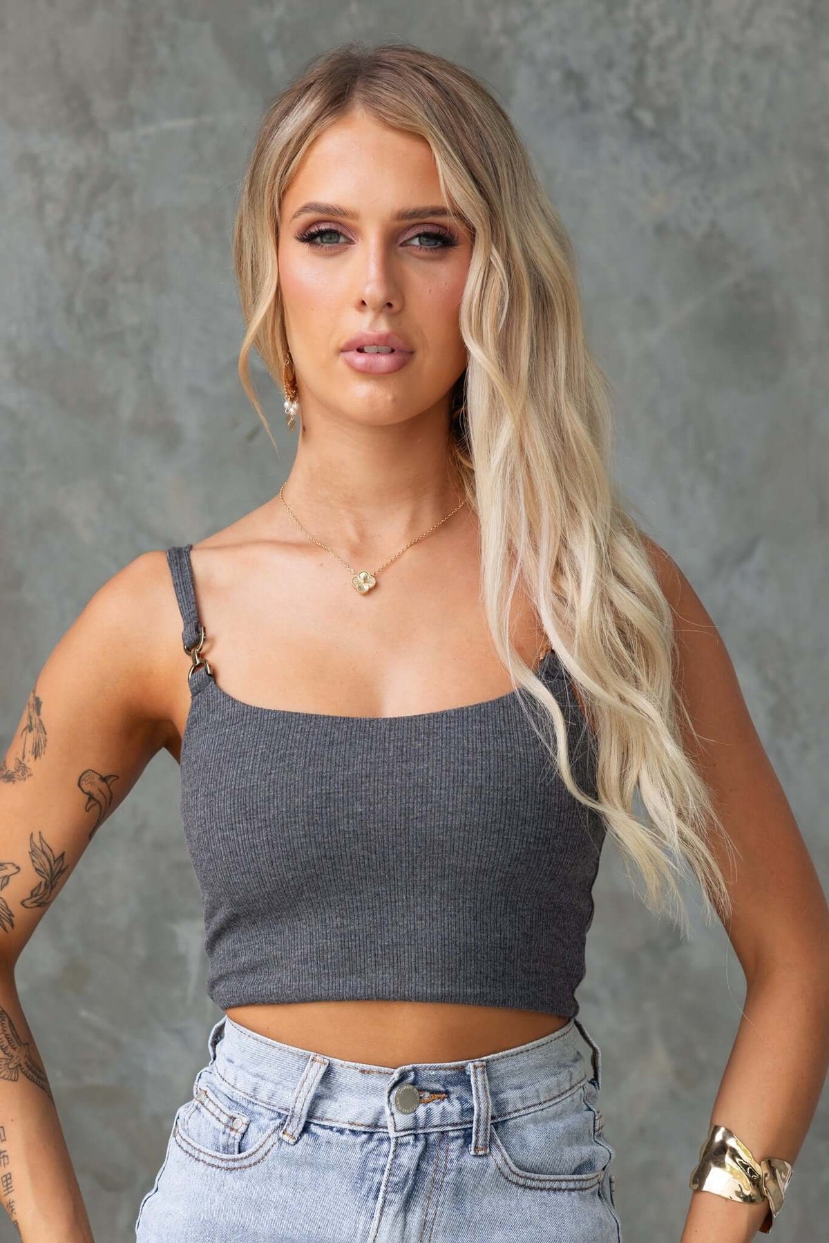 Model wearing the Gapita Top in grey, featuring ribbed material and gold hardware at straps.