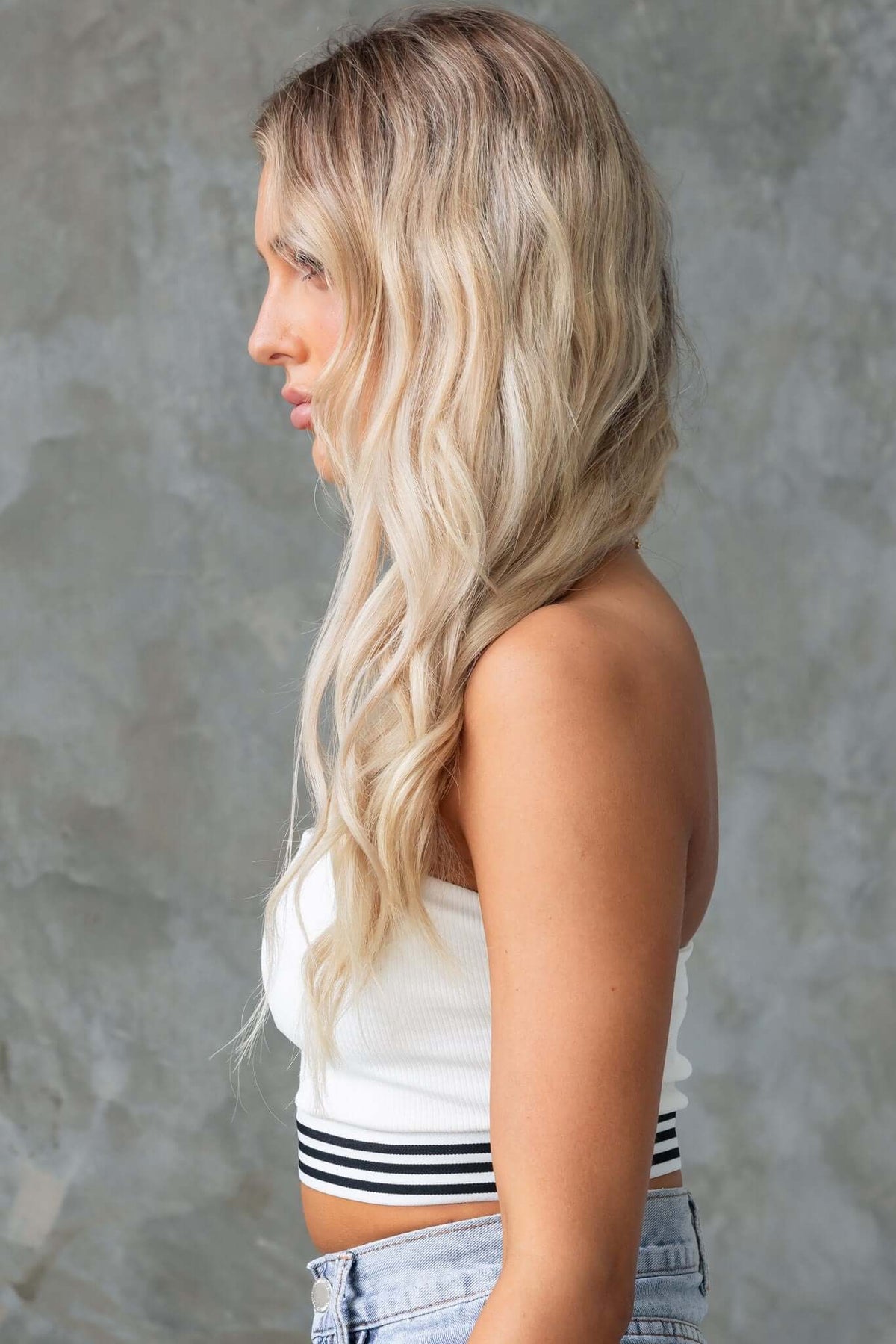 Model showcasing the Brice Top, a ribbed strapless top with an elastic hem, styled with light wash shorts.