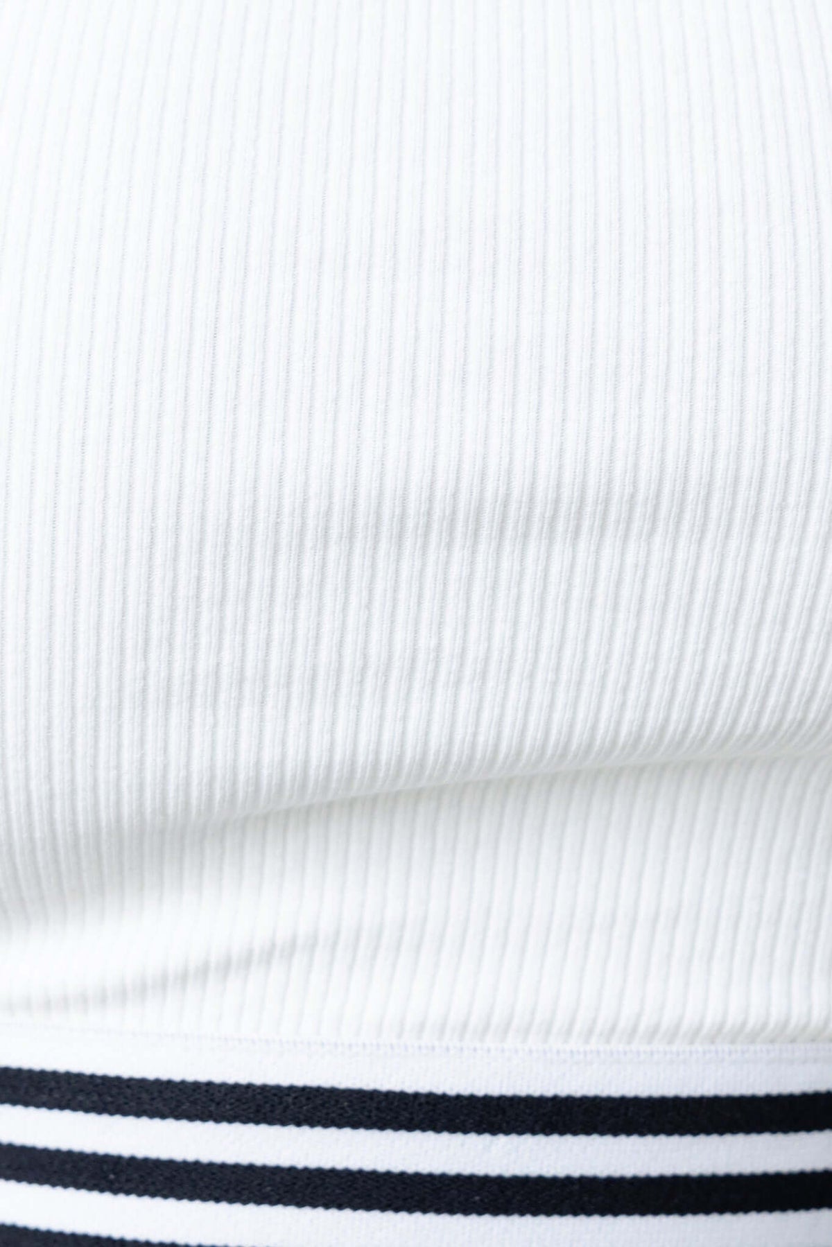 Brice Top in ribbed white material with an elastic hem and lined design, showcasing texture and fit.