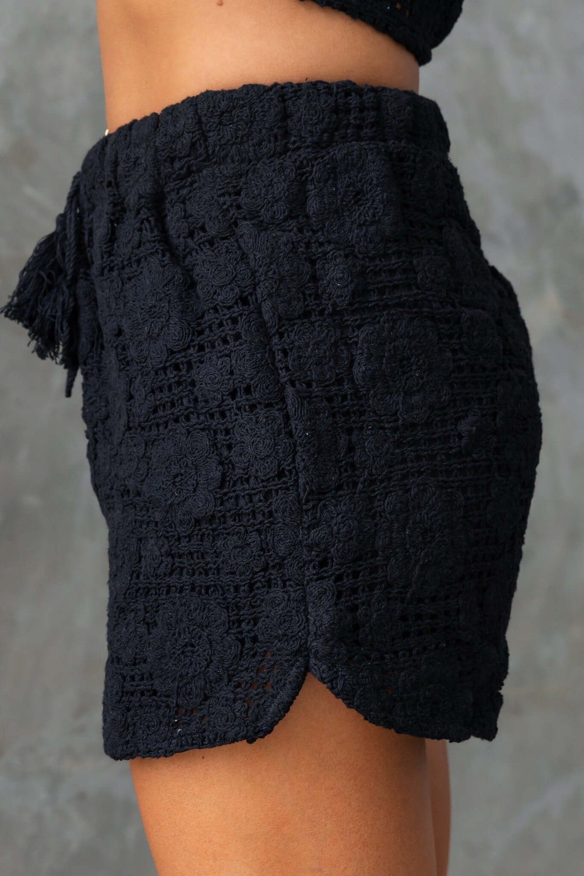 Side view of Fenny Shorts, showcasing a mid-high waist, elastic waistband, and textured fabric in black.