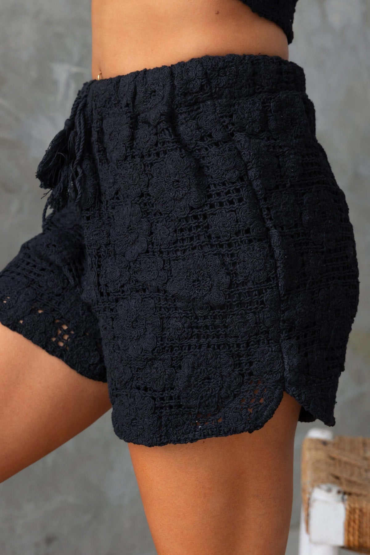 Fenny Shorts in black crochet with mid-high waist and elastic waistband, displaying lace pattern and stylish fit.