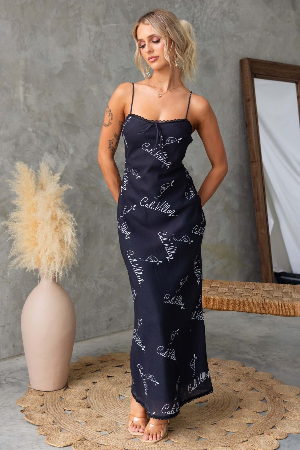 Woman wearing a black Dolomite Maxi Dress with adjustable straps, showcasing a stylish design against a neutral background.