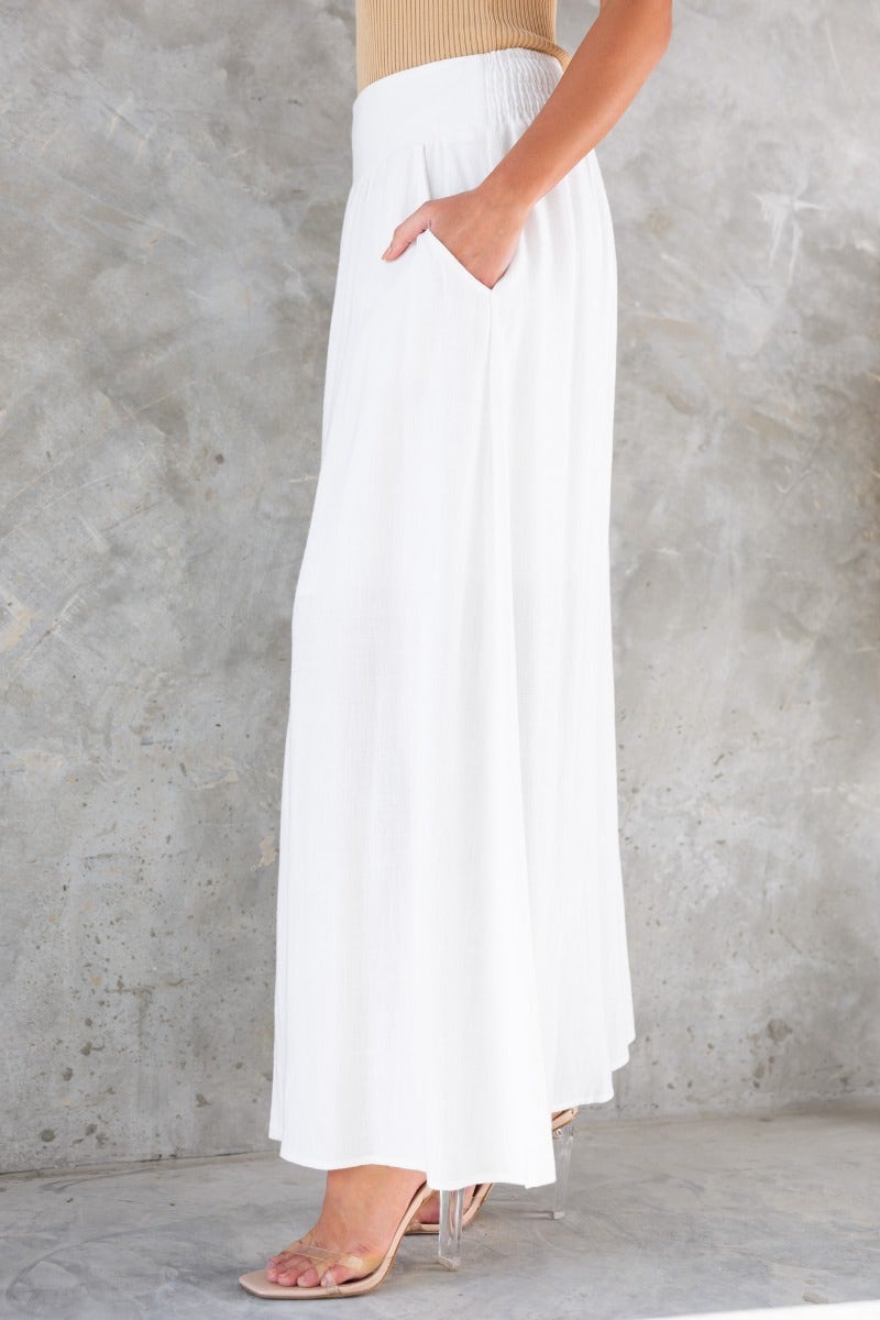 Model wearing Dalila Maxi Skirt, a white linen skirt with pockets and a slit, styled for a chic look.