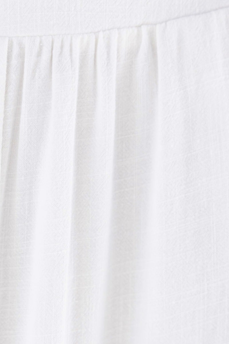 Close-up of white linen fabric featuring gathered detailing of the Dalila Maxi Skirt.