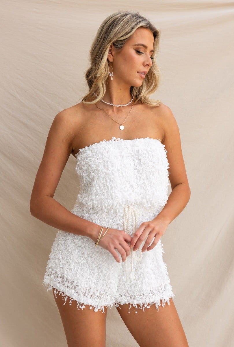 Model wearing a strapless white Zoey Playsuit featuring textured material, adjustable drawstring, and semi-sheer lining.