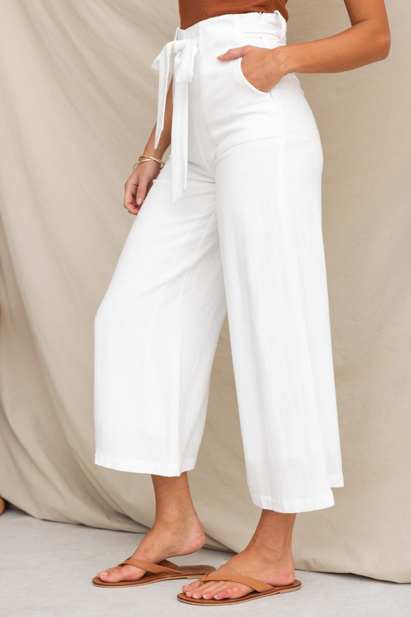 White linen pants with mid-high waist, removable tie, and pockets, styled with sandals.