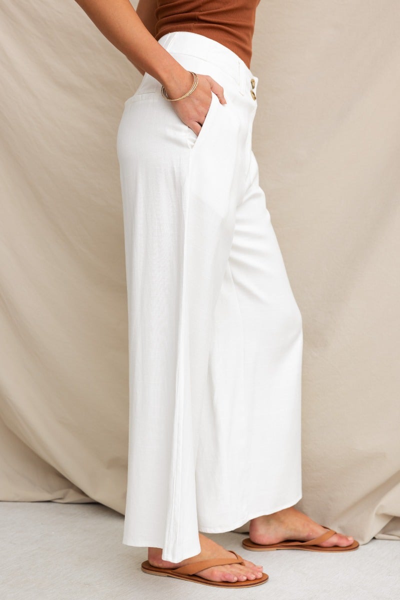 Stylish white silk blend wide leg pants with pockets, mid-high waist fit, modeled by a woman in brown top.