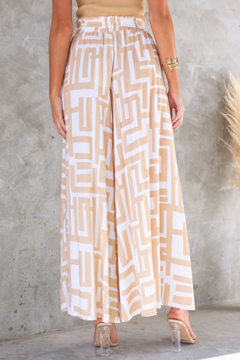 Esmie Pants featuring a geometric print, elastic waistband, and relaxed fit, styled with a casual top against a textured background.