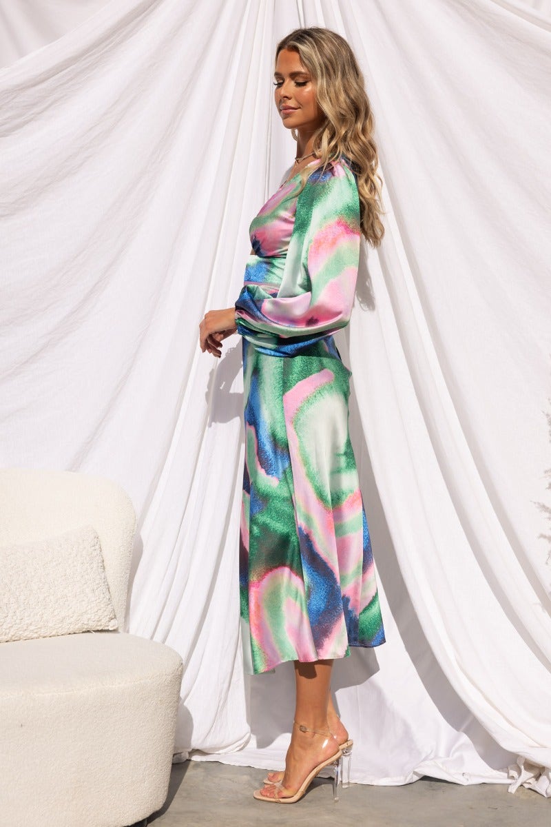 Model wearing a colorful Milani midi dress with V-neckline and cut-out detail, styled against a white backdrop.