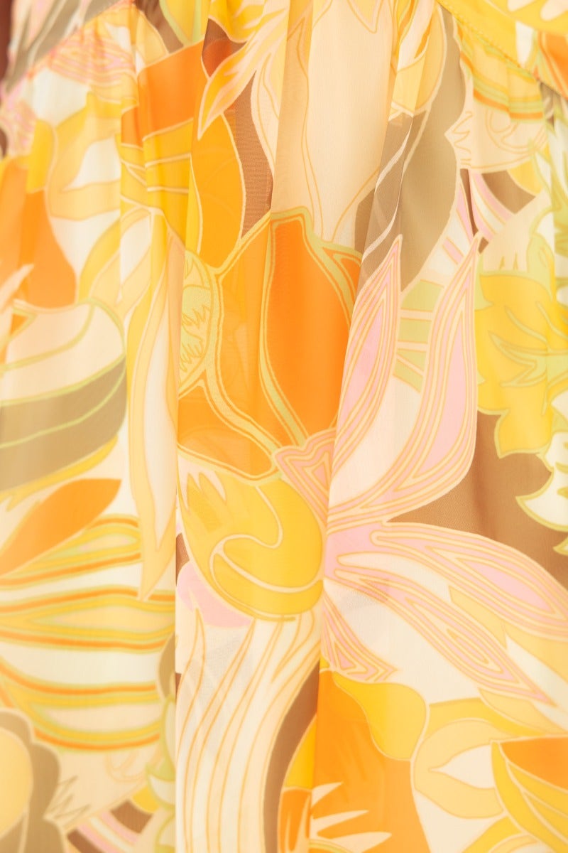 Close-up of colorful floral print fabric in shades of orange and yellow, featured on the Blancia Maxi Dress.