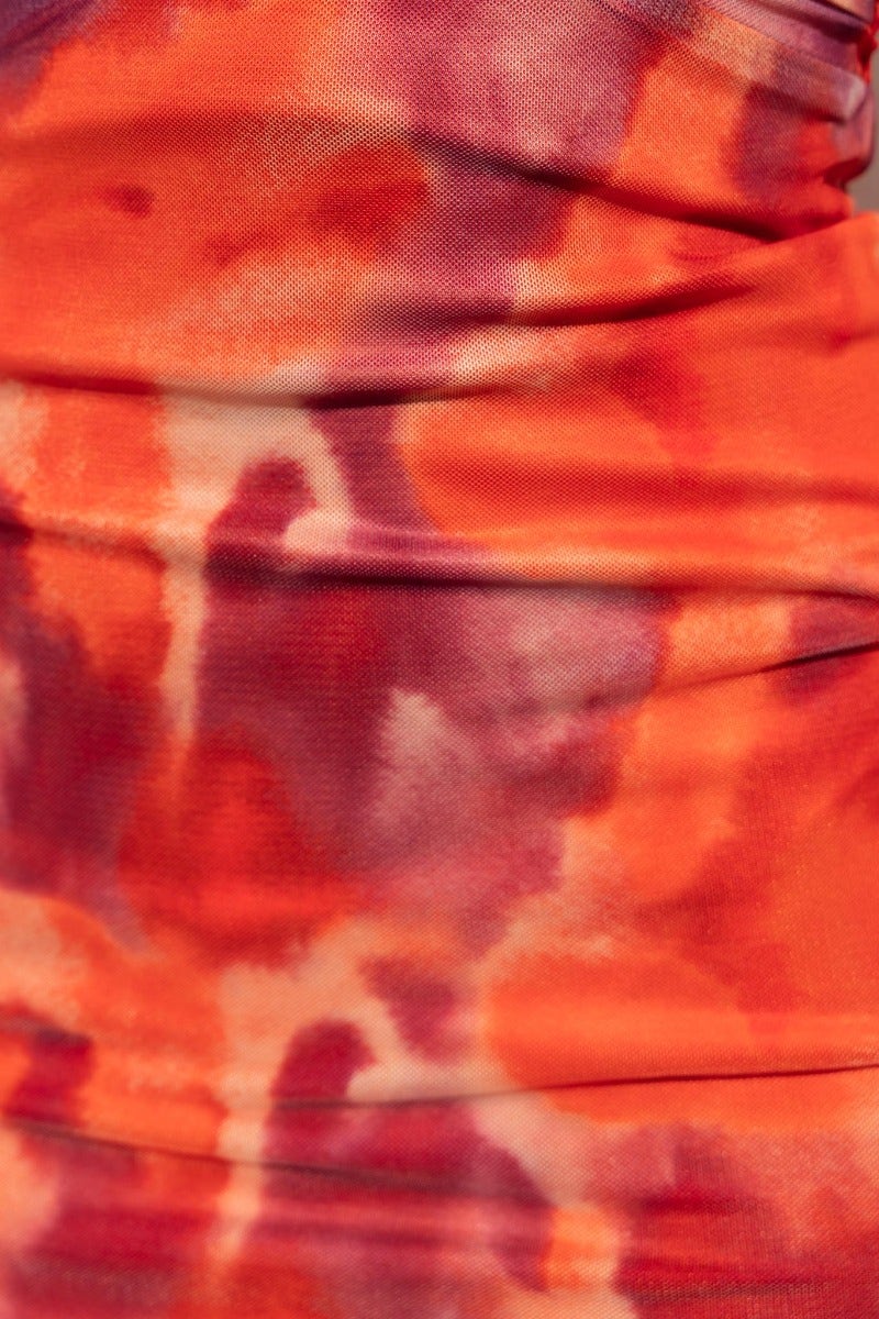 Close-up of vibrant orange and purple tie-dye fabric with soft texture and gathering details.