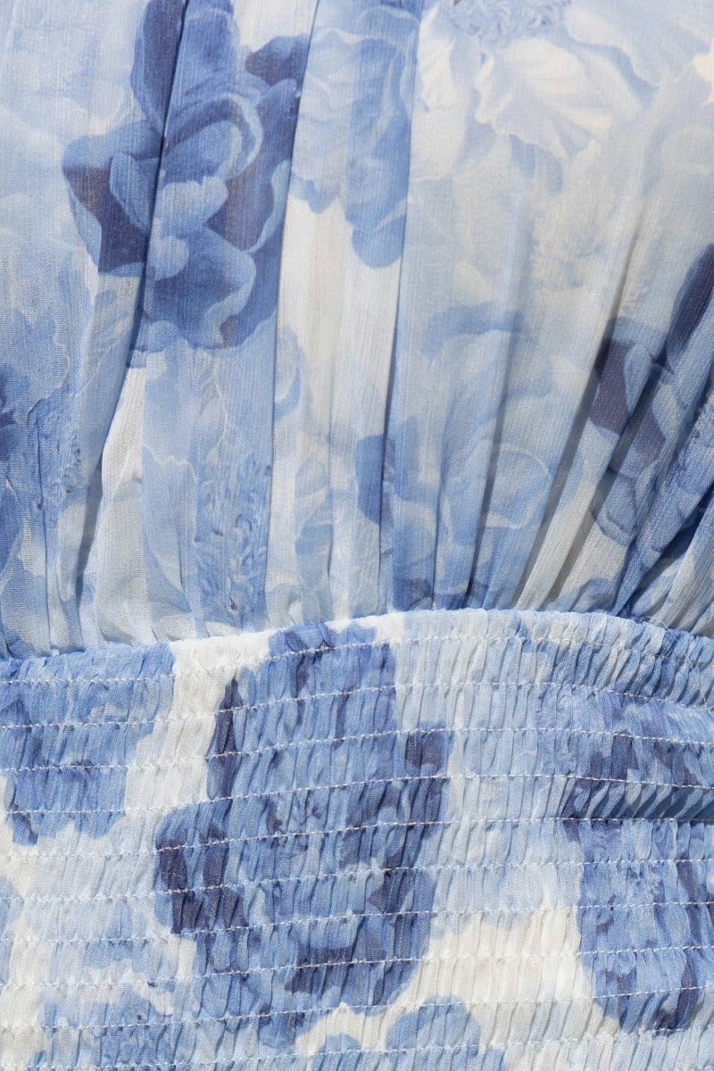 Close-up of the floral print details on the blue Be The Light Dress featuring smocked waist and elegant fabric.