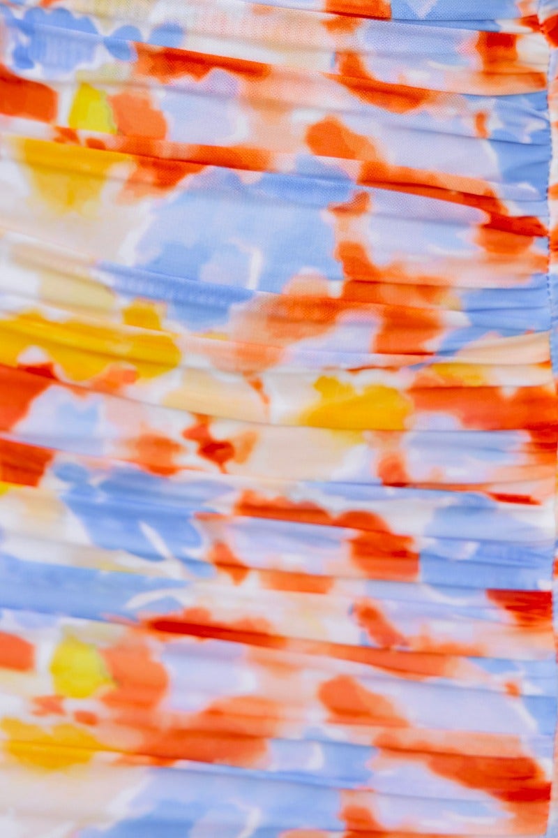Close-up of colorful fabric with ruching, showcasing the vibrant pattern in orange, blue, and yellow hues.