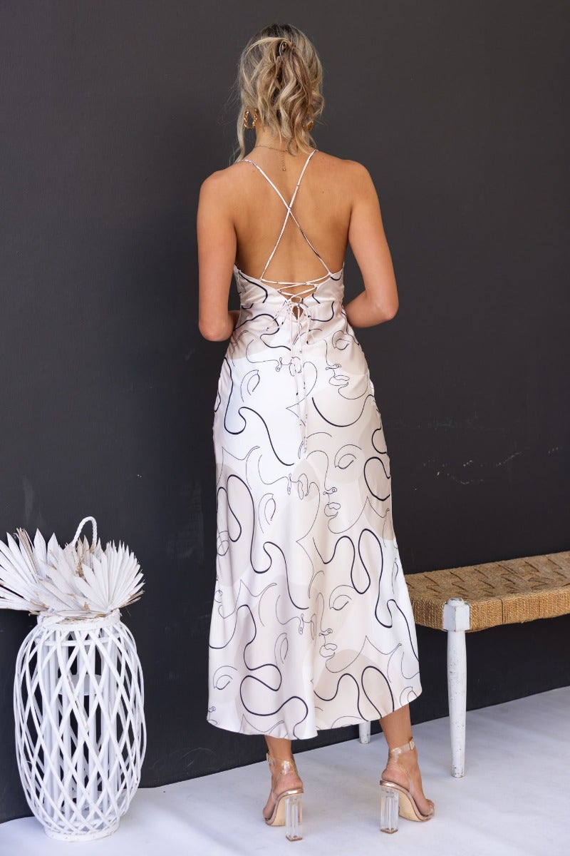 Back view of Derya Maxi Dress featuring adjustable straps, tie detail, and silky pattern on a model.