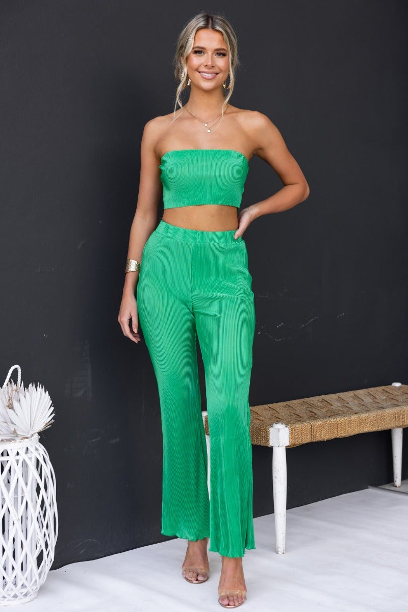 Model wearing Harvie Pants in vibrant green, showcasing accordion pleats and an elastic waistband, perfect for a stylish look.