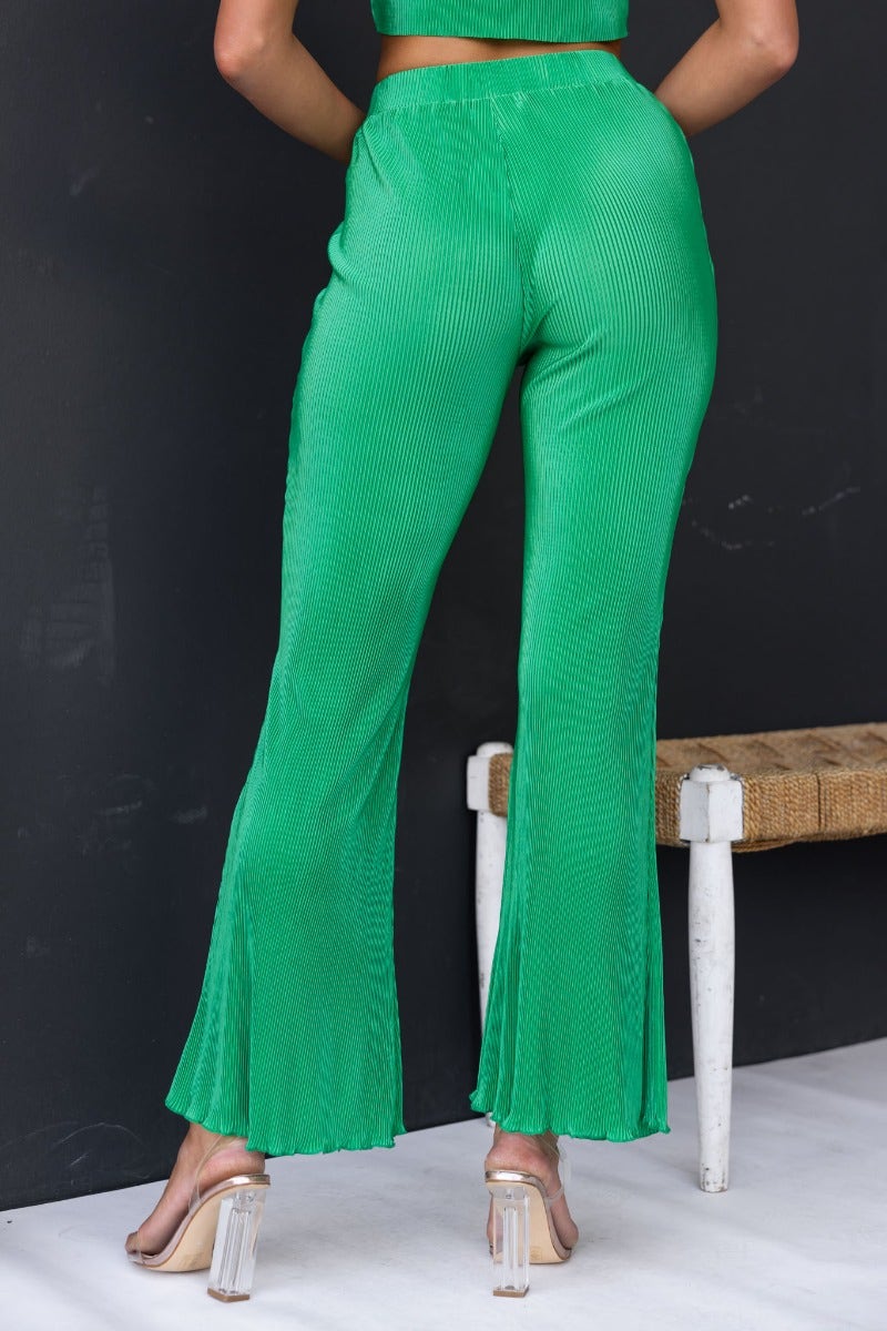 Back view of green accordion pleat Harvie Pants with a flared hem and elastic waistband, perfect for casual wear.