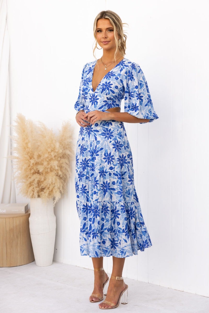 Abeila Maxi Dress featuring a floral print, V-neckline, and cut-out waist in blue and white tones.