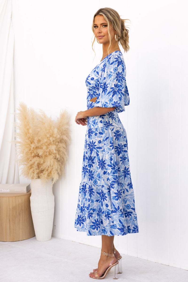 Abeila Maxi Dress featuring a floral print, V-neckline, and cut-out waist, modeled in blue tones.