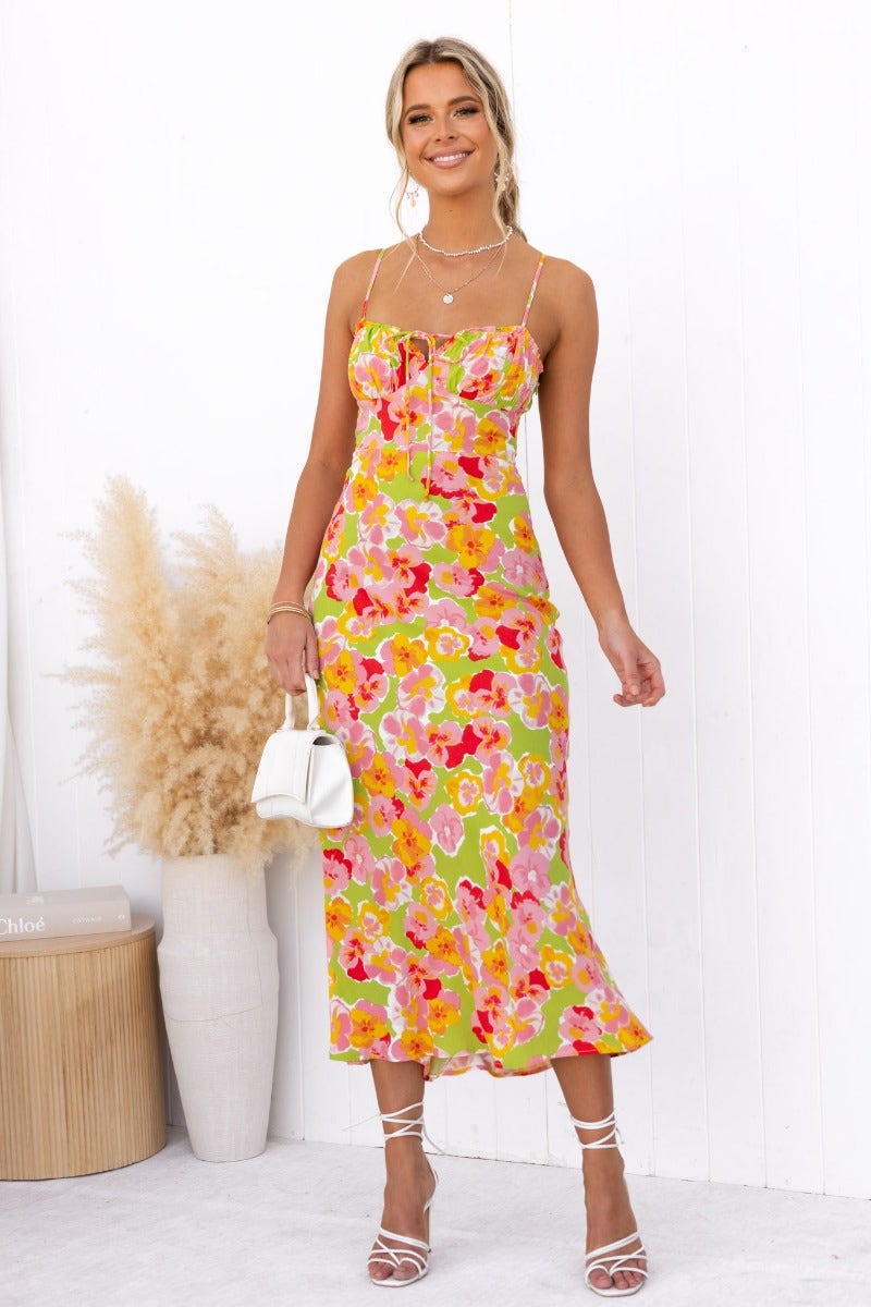 Model wearing an uplifting floral maxi dress with adjustable straps and tie detail at the bust, perfect for summer outings.