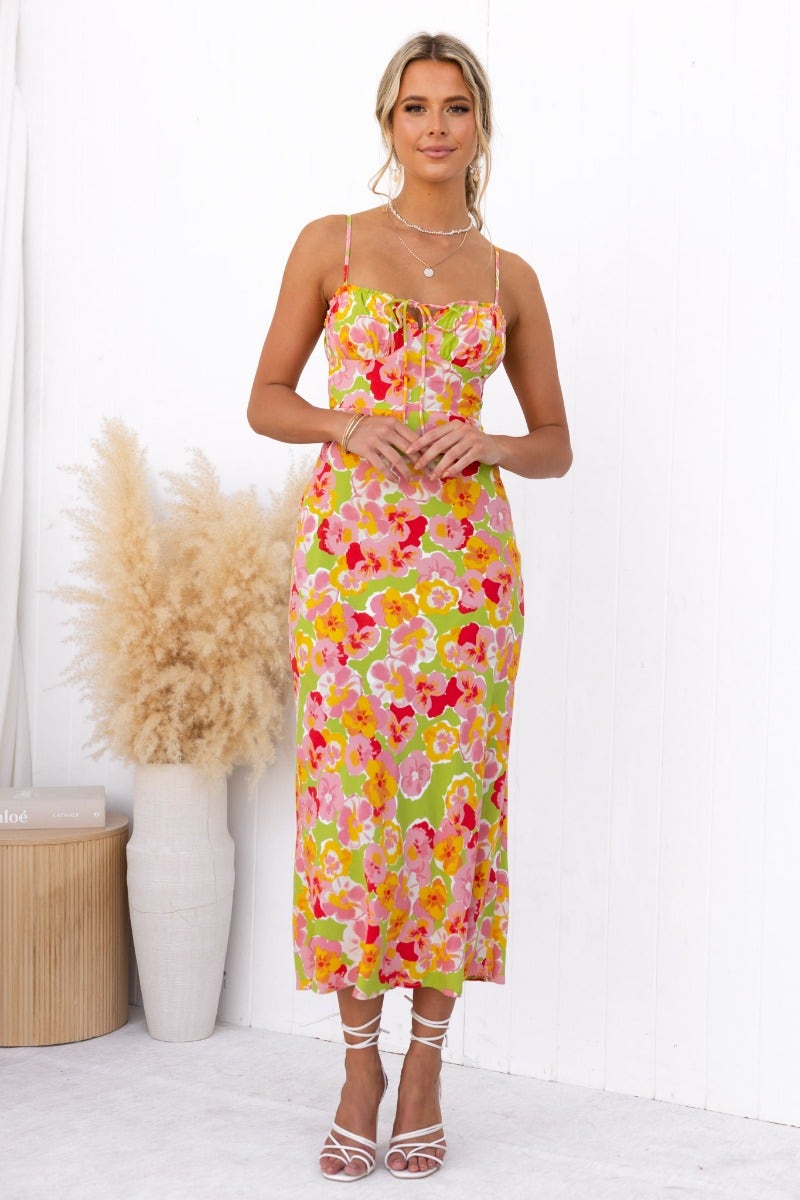 Model wearing a floral uplifting maxi dress with adjustable straps and tie detail at the bust, set against a white backdrop.