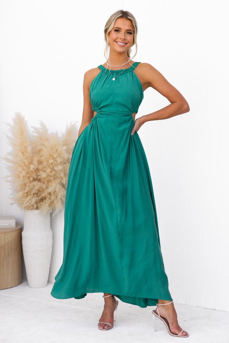 Model wearing the Silvena Maxi Dress in teal, featuring a high neckline, cut-out detail, and pockets.