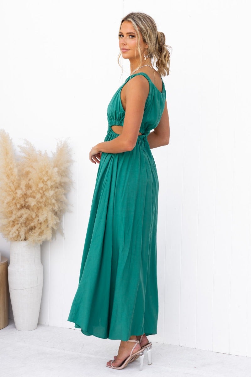 Model showcasing the Silvena Maxi Dress in green, featuring a high neckline, cut-out at waist, and a flowy silhouette.