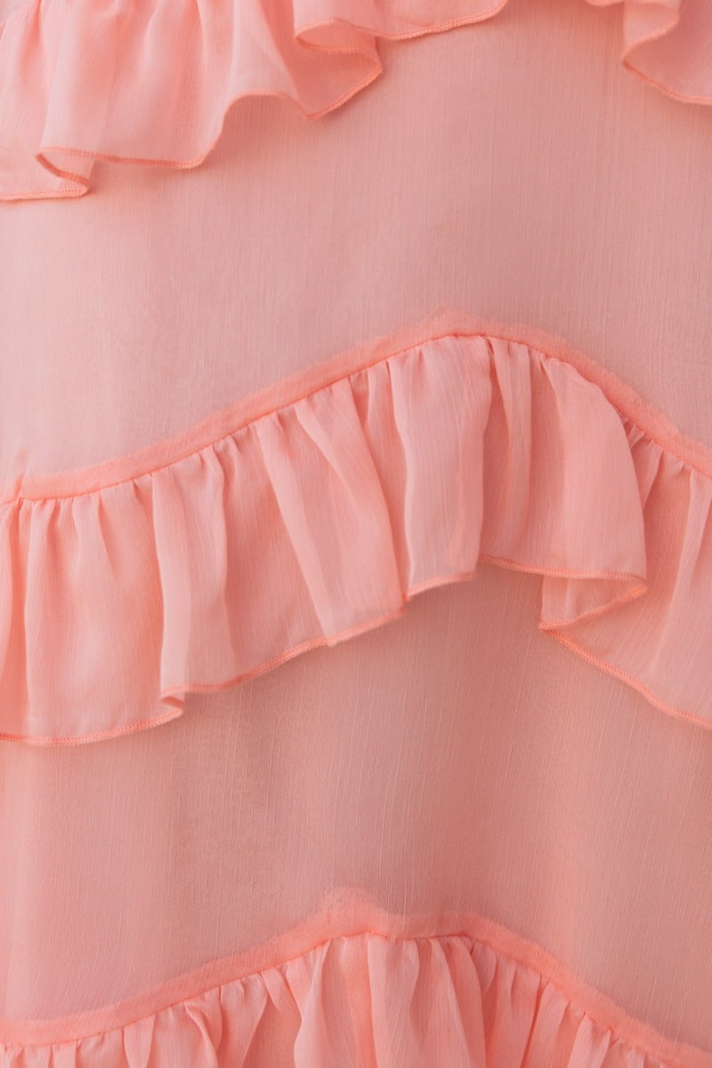 Close-up of soft peach fabric featuring delicate ruffle details, perfect for a stylish and feminine look.