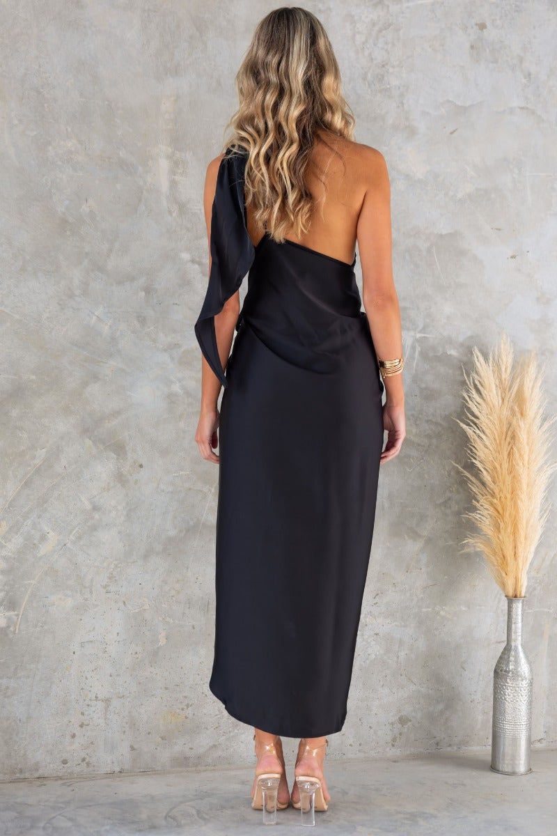 Back view of Remi Wrap Midi Dress in black satin, featuring a one-shoulder design and a wrap style skirt.