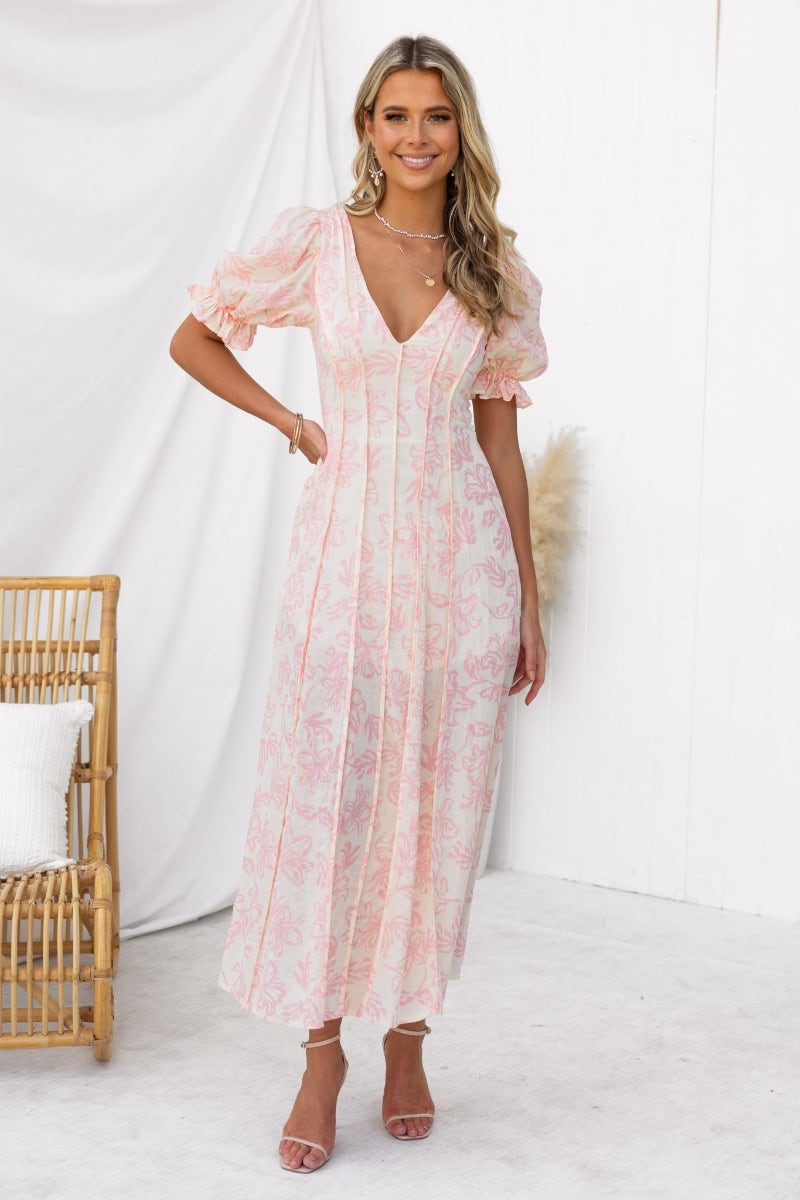 Model wearing Adaline Maxi Dress, a floral print V-neck dress with elastic sleeves and an invisible zip, styled against a chic backdrop.